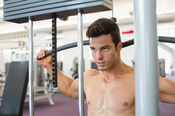 Muskularny mężczyzna ćwiczenia na maszynie lat w siłowni — Zdjęcie stockowe