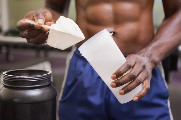 Body builder holding a scoop of protein mix — Stock Photo, Image