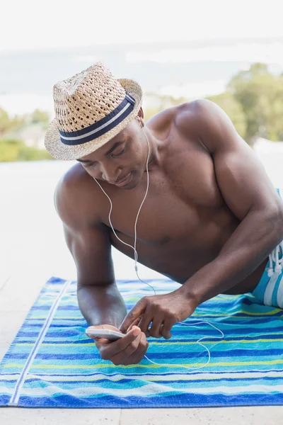 Handsome shirtless man listening to music poolside — Stock Photo, Image