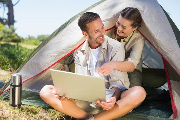 Sportowy kilka patrząc na laptopa poza namiotem — Zdjęcie stockowe