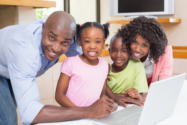 Irmãos bonitos usando laptop junto com os pais — Fotografia de Stock