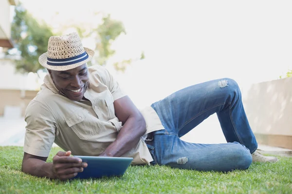 Uomo sorridente rilassante nel suo giardino utilizzando tablet pc — Foto Stock