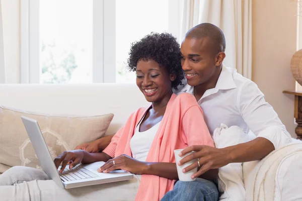 Casal bonito relaxante no sofá com laptop e café — Fotografia de Stock