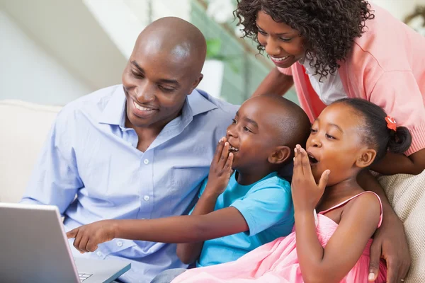 Família relaxando juntos no sofá usando laptop — Fotografia de Stock