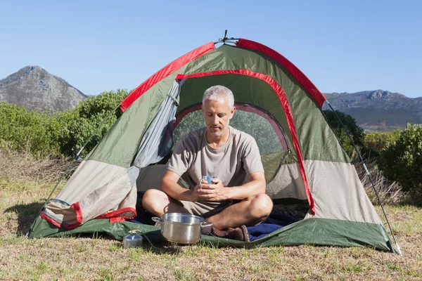 Felice camper tenendo tazza fuori dalla sua tenda — Foto Stock