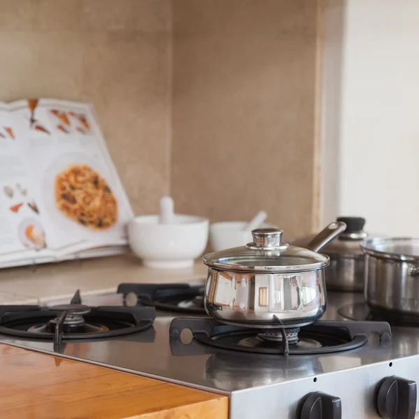 Stove top with saucepan and recipe book — Stock Photo, Image