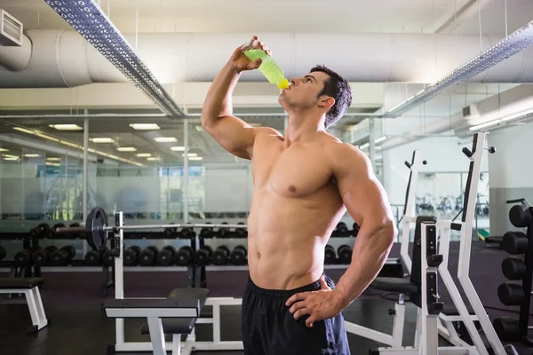 Uomo muscoloso senza maglietta bere bevanda energetica in palestra — Foto Stock