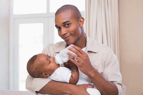 Pai feliz alimentando seu bebê menino uma mamadeira — Fotografia de Stock