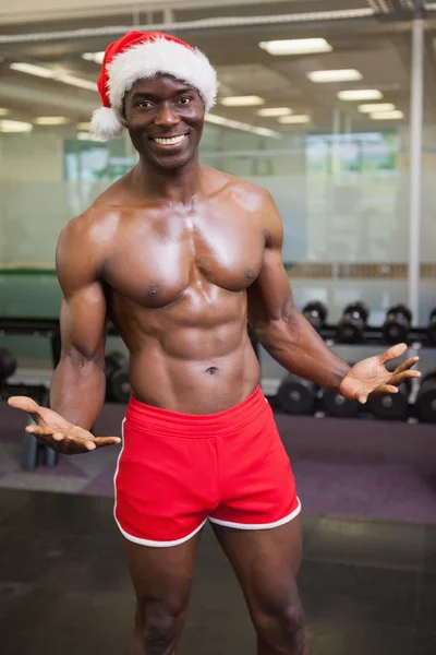 Hombre macho sin camisa en sombrero de santa en el gimnasio — Foto de Stock