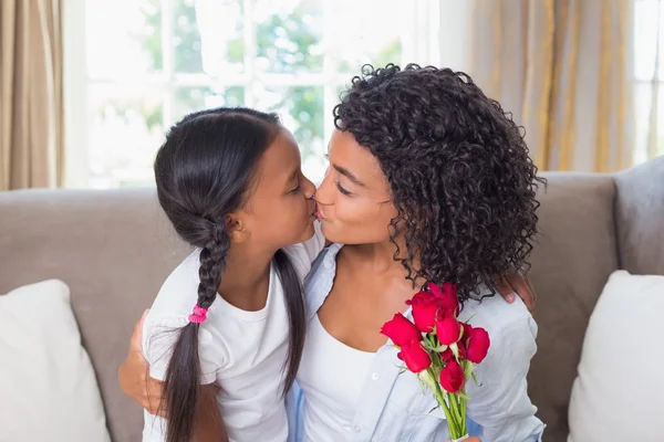 Mãe bonita beijando sua filha segurando rosas — Fotografia de Stock