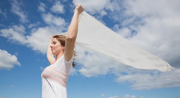 Woman holding out scarf against blue sky and clouds — Stock Photo, Image