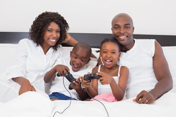 Family playing video games together in bed — Stock Photo, Image