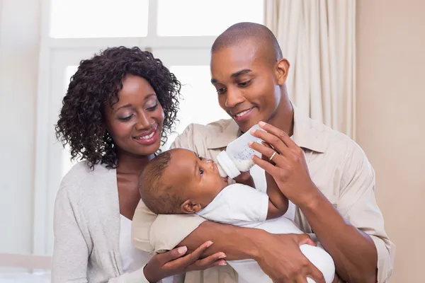 Pais felizes alimentando seu bebê menino uma mamadeira — Fotografia de Stock
