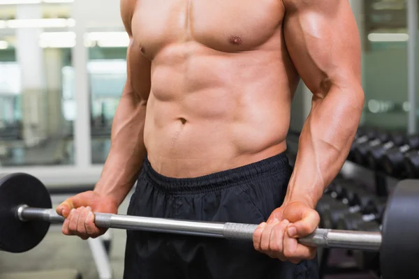 Mid section of a shirtless muscular man lifting barbell — Stock Photo, Image