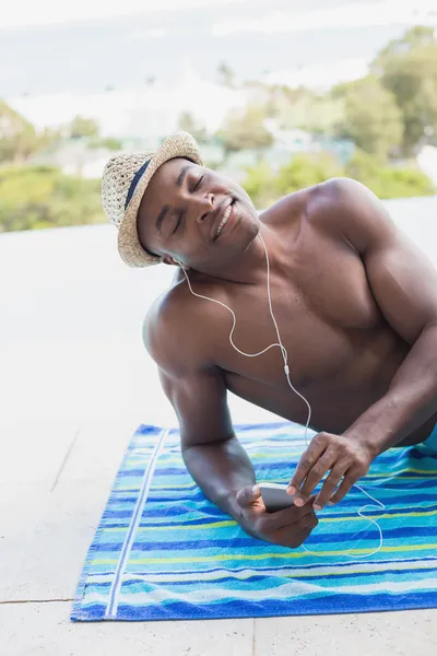 Handsome shirtless man listening to music poolside — Stock Photo, Image