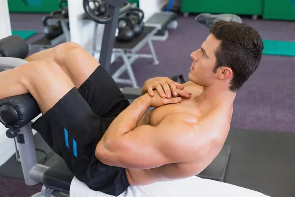 Homem muscular fazendo abdominais crunches no ginásio — Fotografia de Stock