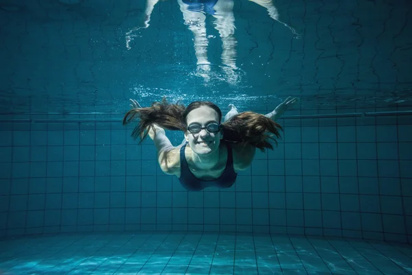 Nadador atlético sonriendo a la cámara bajo el agua — Foto de Stock