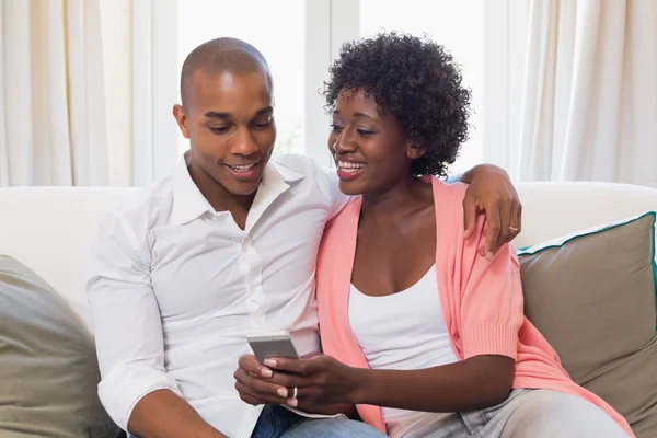 Linda pareja relajante en el sofá con teléfono inteligente —  Fotos de Stock