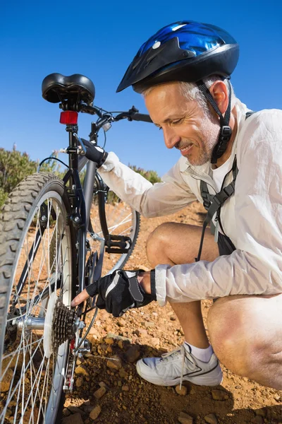 Smiing cycliste fixer sa chaîne de vélo sur le terrain de la campagne — Photo