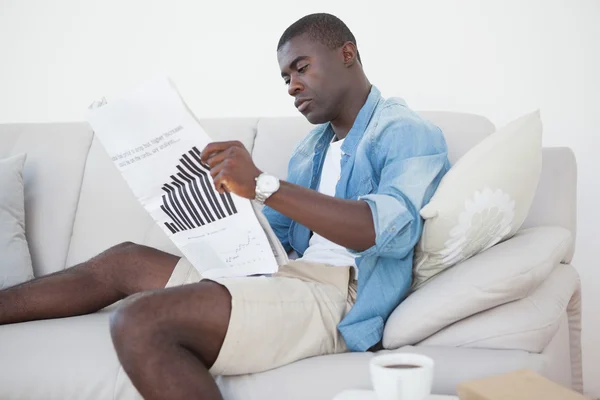 Homme décontracté assis sur le canapé lisant le journal — Photo