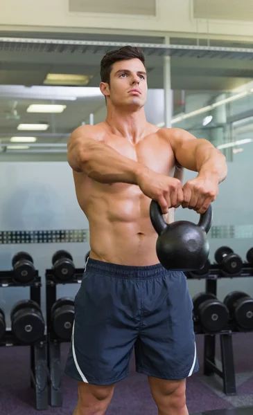 Muscular man lifting kettle bell in gym — Stock Photo, Image