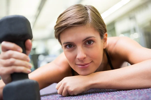 Fit brunette lying on floor with dumbbell — Stock Photo, Image