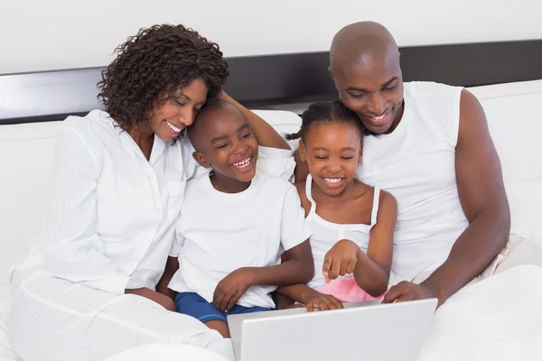 Familia feliz usando el ordenador portátil juntos en la cama — Foto de Stock