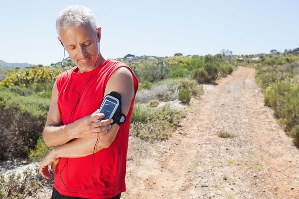 Fit man changer la chanson sur son lecteur de musique sur le sentier de montagne — Photo