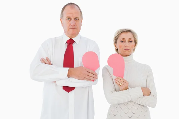 Older couple standing holding broken pink heart — Stock Photo, Image