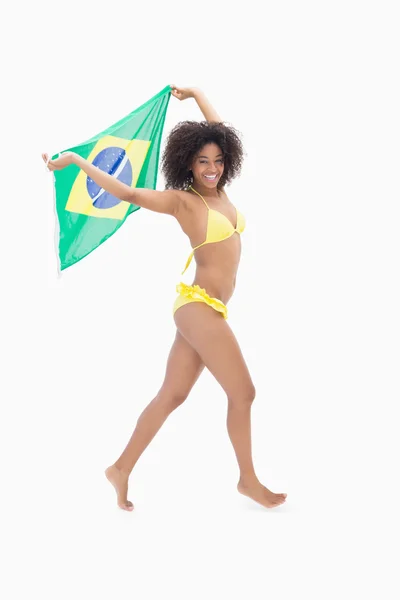 Athletic girl in yellow bikini holding brazil flag — Stock Photo, Image