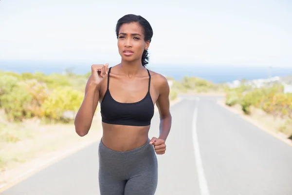 Donna in forma che corre lungo la strada aperta — Foto Stock