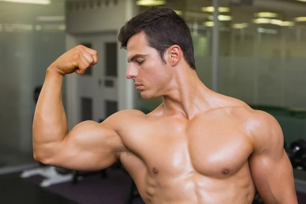 Muscular man flexing muscles in gym — Stock Photo, Image