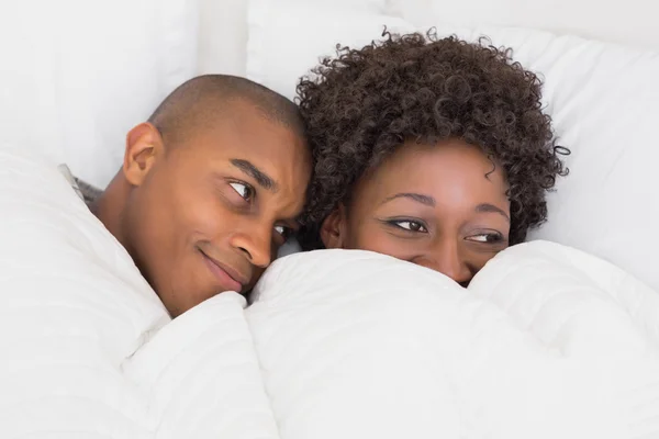 Šťastný pár leží v posteli pod peřinou — Stock fotografie