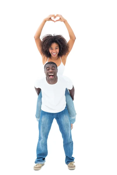 Casual man giving his smiling girlfriend a piggy back — Stock Photo, Image