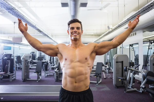 Shirtless bodybuilder with arms raised in gym — Stock Photo, Image