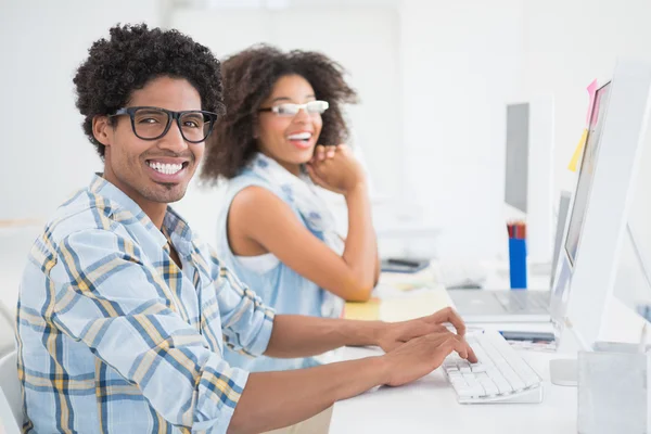 Equipo de diseño feliz sonriendo a la cámara trabajando en el escritorio —  Fotos de Stock