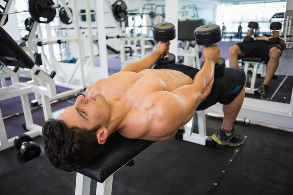 Homem musculoso exercitando com halteres no ginásio — Fotografia de Stock