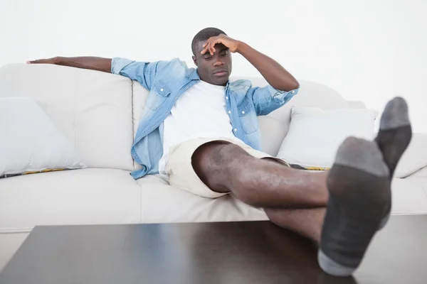 Lässiger Mann sitzt mit hochgezogenen Füßen auf Sofa — Stockfoto