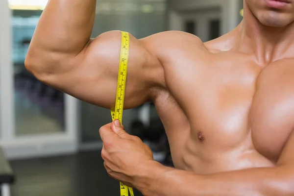 Homem muscular medindo bíceps — Fotografia de Stock