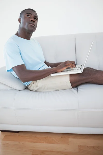 Przypadkowy mężczyzna siedzi na kanapie przy użyciu laptopa — Zdjęcie stockowe