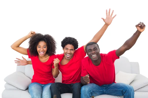 Aficionados al fútbol en rojo animando en el sofá — Foto de Stock