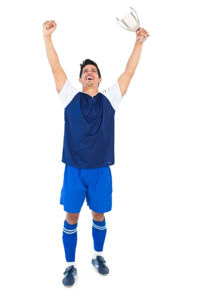 Jogador de futebol em azul segurando copo vencedores — Fotografia de Stock