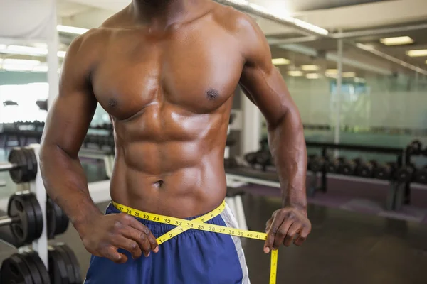 Hombre musculoso midiendo cintura en gimnasio —  Fotos de Stock