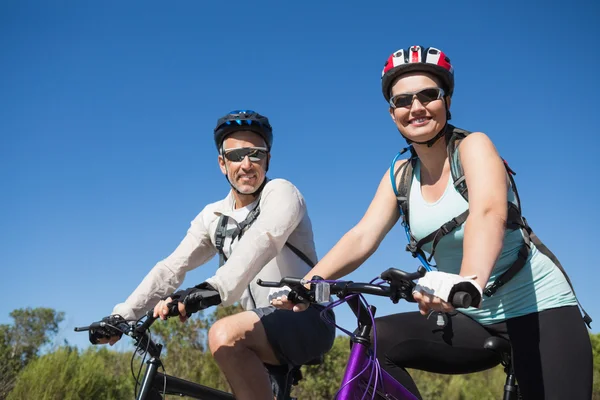 Ativo casal feliz indo para um passeio de bicicleta no campo — Fotografia de Stock