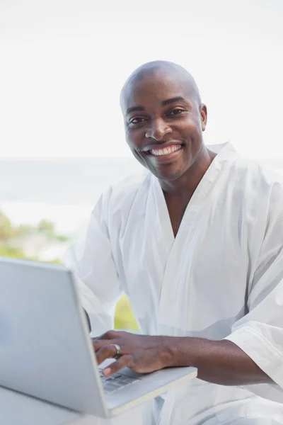 Handsome man in bathrobe using laptop outside — Stock Photo, Image