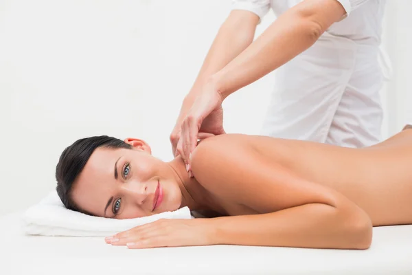 Schöne Brünette genießt eine Rückenmassage lächelnd in die Kamera — Stockfoto