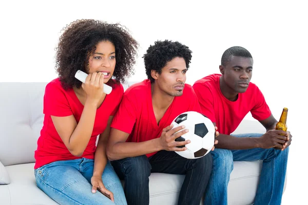 Nervous football fans in red sitting on couch — Stock Photo, Image