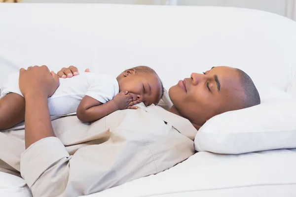 Glücklicher junger Vater, der mit seinem kleinen Sohn auf der Couch schläft — Stockfoto