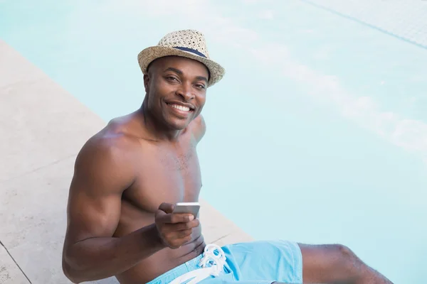 Bello uomo senza camicia che messaggia al telefono a bordo piscina — Foto Stock