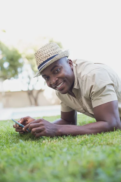Smiling man relaxing in his garden texting on phone — Stock Photo, Image